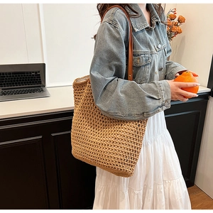 Detailed view of handmade woven straw tote bag with brown faux leather shoulder straps