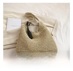 Detailed view of handmade woven straw tote bag with brown leather tassel and handle