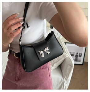 Close-up of black leather baguette bag with a stylish silver metal bow buckle detail