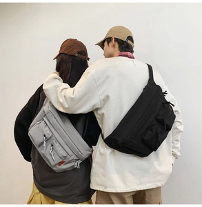 Détail de sacs bandoulière utilitaires gris et noirs avec grands compartiments et poches