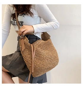 Detail of woven straw crossbody bag with brown leather strap and bohemian texture