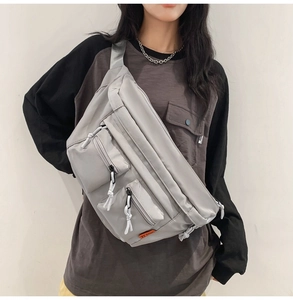 Détail du sac de poitrine en nylon gris clair avec fermetures éclair et étiquette orange