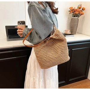 Detail of hand-woven straw tote bag with grid pattern and brown leather straps