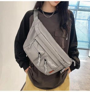 Détail du sac à bandoulière en nylon gris avec doubles poches zippées et sangle large