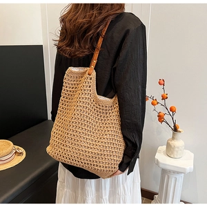 Detail of hand-woven straw tote bag with brown leather straps and hollow mesh texture