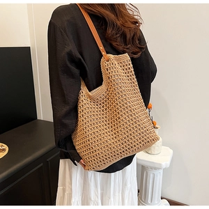 Detail of woven straw shoulder bag with leather strap and metal rivet reinforcement