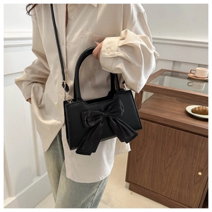 Sac bandoulière tendance en similicuir noir avec grand nœud décoratif sur mannequin