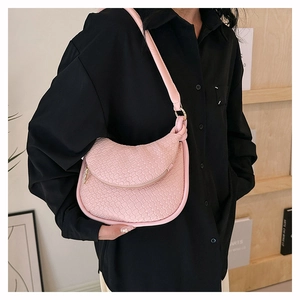 Gros plan sur la texture tissée rose d'un sac demi-lune en cuir PU avec fermeture