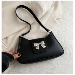 Fashionable black PU leather shoulder bag with a silver bow ornament on a suit jacket