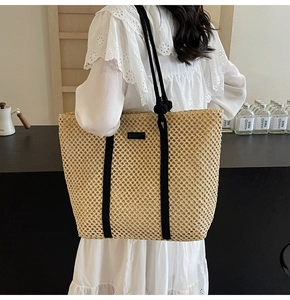 Detail of hollow woven tote bag with beige straw texture and black rope shoulder straps
