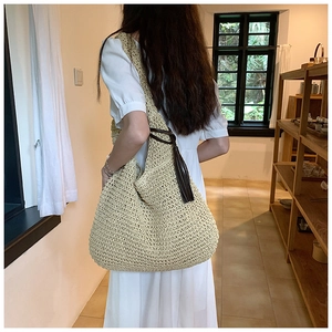 Detail of the woven texture and brown leather strap with fringe on this beige tote