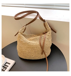 Detail of woven straw tote bag featuring brown leather strap and drawstring closure