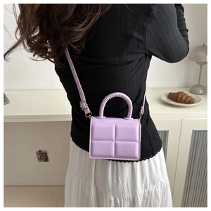 Detail view of light purple quilted PU handbag styled in a modern minimalist interior