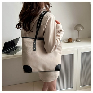 Detail of a large white tote bag with black trim and reinforced golden rivets