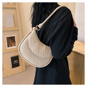 Texture détaillée d'un sac à bandoulière hobo tressé crème porté par un mannequin