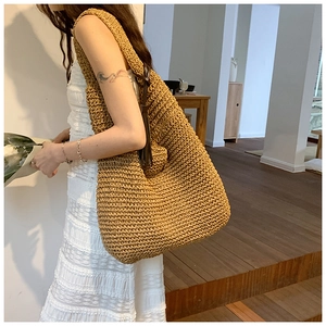 Detail of hand-woven straw tote bag with leather tassel on a white lace dress model