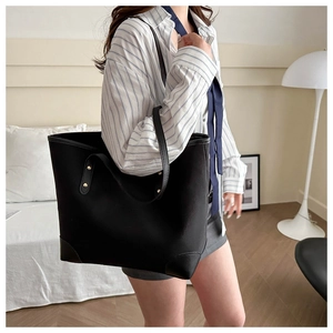 Chic black tote bag with leather reinforcement and metallic rivets shown in a lifestyle setting