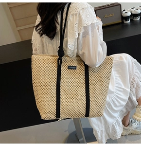 Beige straw tote bag with black rope handles and lace dress on a summer vacation model