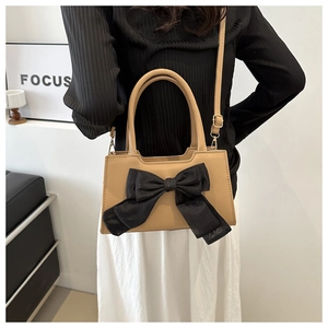 Sac bandoulière beige en PU avec nœud en maille noire porté par un mannequin