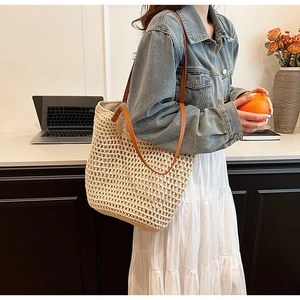 Detailed close-up of woven straw tote bag with brown leather handles in a home setting