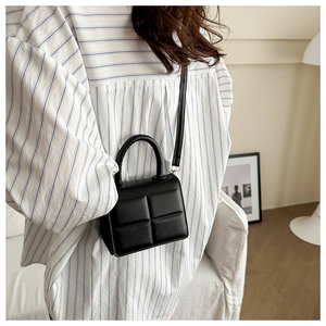 Close-up of black quilted PU leather crossbody bag with top handle and slim strap