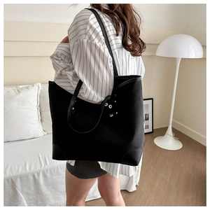 Close-up of a large black canvas tote bag with funny eye charm in a modern home setting