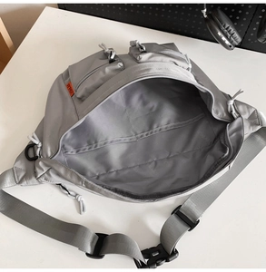 Détail du sac de poitrine en nylon gris multi-poches avec compartiments et étiquette orange