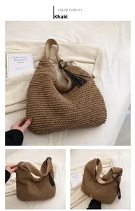 Detail view of khaki straw woven tote bag featuring black tassel and refined textures