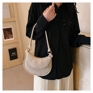 Détail de la texture tressée en similicuir crème sur un sac à bandoulière minimaliste chic