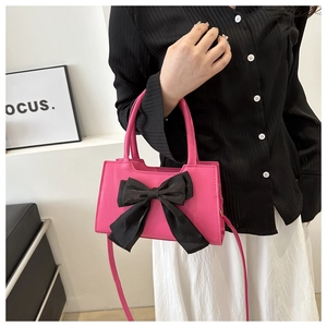 Détail d'un sac bandoulière en cuir PU rose avec un grand nœud décoratif en tissu noir
