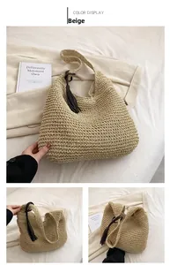 Detail of beige hand-woven straw tote bag with brown leather tassel and natural texture