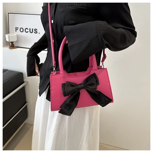 Détail d'un sac à main rose vif en similicuir avec un grand nœud en satin noir élégant
