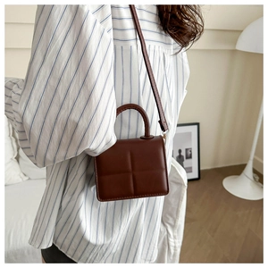 Brown PU leather crossbody bag with cross-grain texture worn by a model in a cozy interior