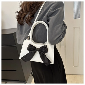 Vue détaillée du sac à main blanc en cuir PU avec un grand nœud noir et détails dorés