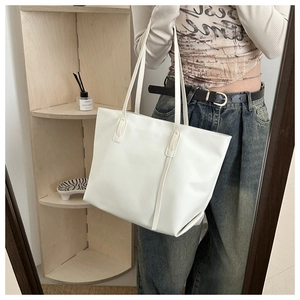Vista dettagliata della borsa tote bianca in ecopelle su uno scaffale in legno minimalista