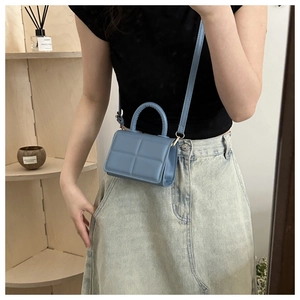 Model wearing light blue quilted mini flap bag with golden hardware and round handle
