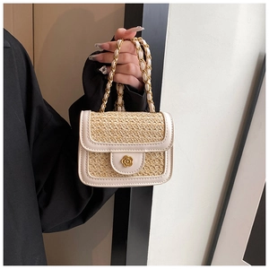 Dettaglio borsa beige in paglia intrecciata con chiusura a fiore dorato e catena