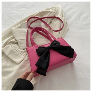 Sac bandoulière en PU rose avec grand nœud en satin noir sur fond blanc