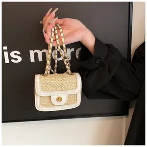 Dettaglio mini borsa in paglia intrecciata con chiusura a fiore dorato e bordo bianco