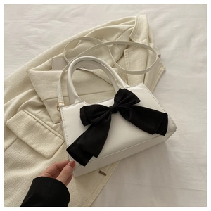 Sac bandoulière élégant en cuir PU blanc avec un grand nœud noir sur un fond de tissu épuré