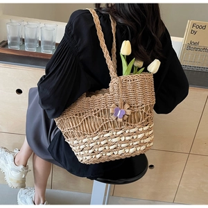 Détail d'un sac en paille tressée avec contraste beige et charm papillon violet