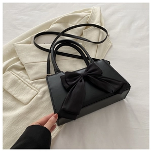 Sac bandoulière tendance en cuir PU noir avec un grand nœud sur fond de costume crème