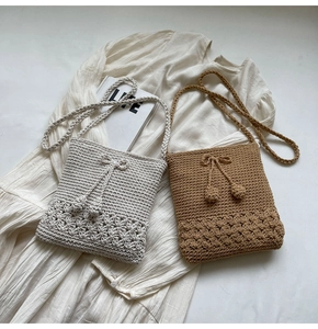 Detail der handgestrickten Mini-Quadrat-Tasche mit hohlem Blumenmuster und Bommeln