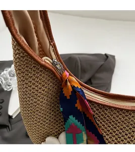 Detailed close-up of smooth metal zipper and floral silk scarf on woven straw tote bag
