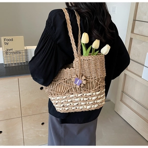 Détail du sac cabas en paille tissé à la main avec pendentif papillon violet et base crème