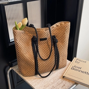 Fashionable straw tote bag with black rope handles and minimalist woven texture design