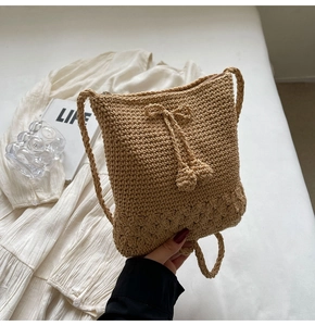 Detail der khakifarbenen Strohtasche mit floralem Häkelboden und Quasten-Kordelzug