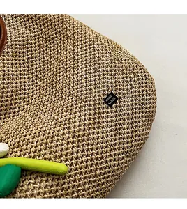 Close-up of hand-woven straw tote texture with black handmade label and green leaf detail
