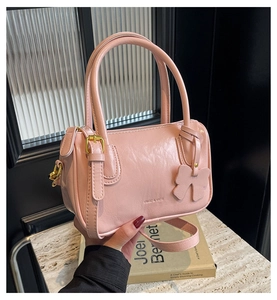 Close-up of pink textured PU leather Boston bag with a bow charm and gold hardware