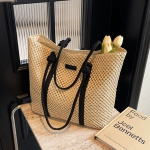 Fashionable hollow straw woven tote bag with black rope handles and minimal beige design